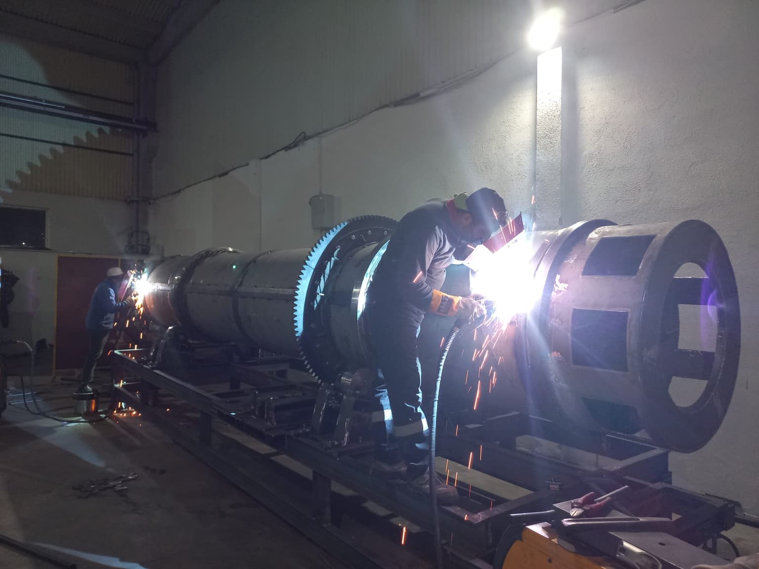Welders fabricating rotary dryer gear ring in Lozzar Process workshop — sparks flying